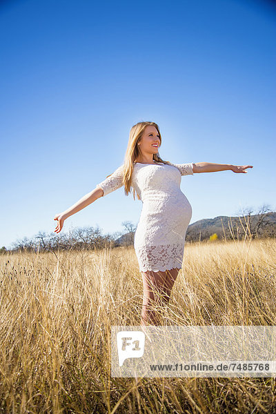 USA  Texas  Schwangere junge Frau  die die Arme streckt  lächelnd