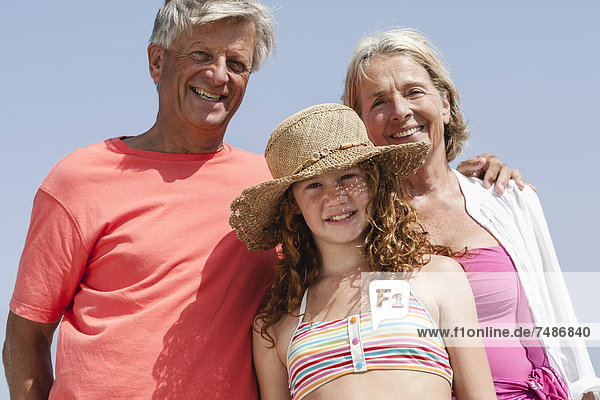 Spanien  Großeltern mit Enkelin am Strand  lächelnd  Portrait