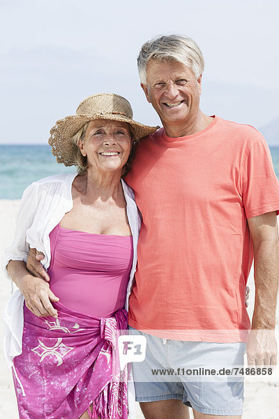 Spanien  Seniorenpaar am Strand stehend  lächelnd  Portrait
