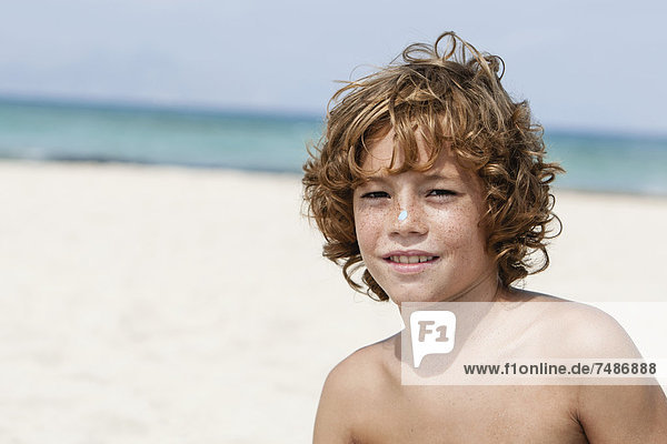 Spanien  Junge am Strand sitzend  lächelnd
