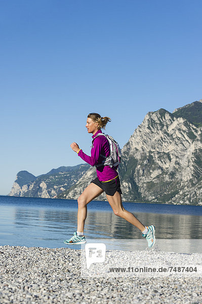 Italy  Mid adult woman jogging by Lake Garda