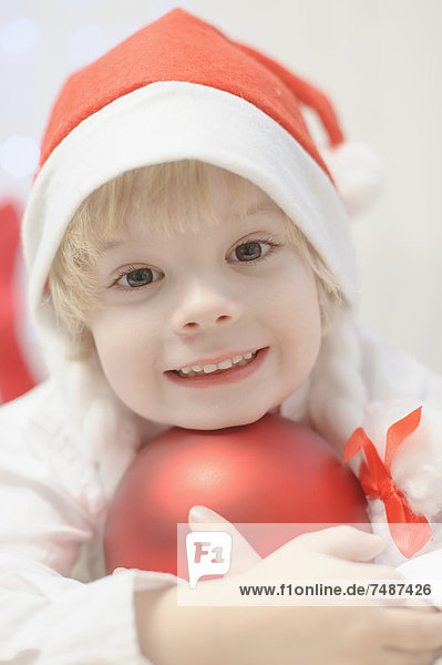 Junge mit Weihnachtskugel  lächelnd  Portrait