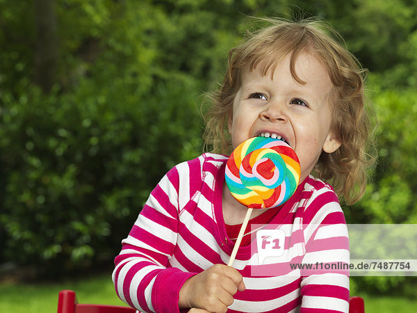 Girl sitting outside and eating lollipop