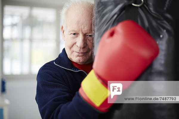 Senior Mann mit Boxhandschuh und Boxsack