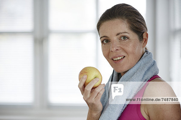 Reife Frau isst Apfel  lächelnd