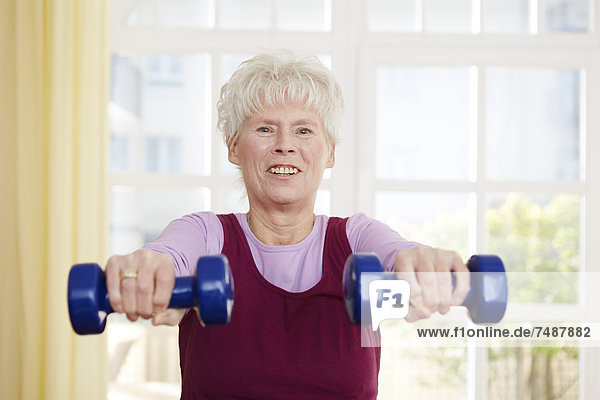 Senior woman exercising with barbell  smiling