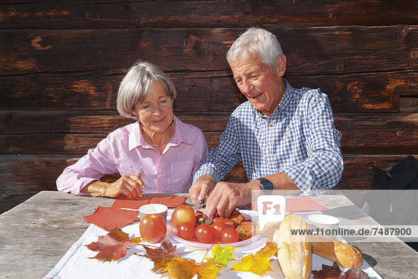 Deutschland  Bayern  Seniorenpaar beim Essen auf der Berghütte