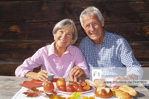 Deutschland  Bayern  Seniorenpaar beim Essen auf der Berghütte