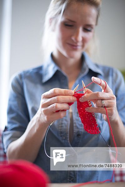 Junge Frau strickt mit rotem Garn