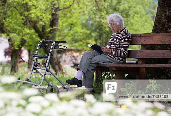 Austria  Senior woman sitting on bench and reading book