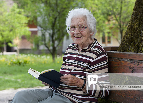 Austria  Senior woman sitting on bench and reading book