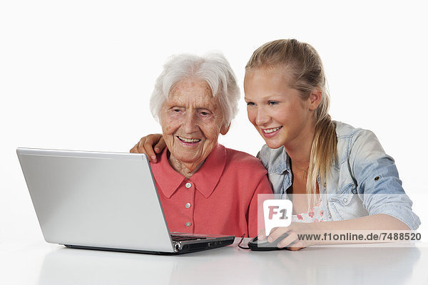 Seniorin und Teenagerin mit Laptop  lächelnd