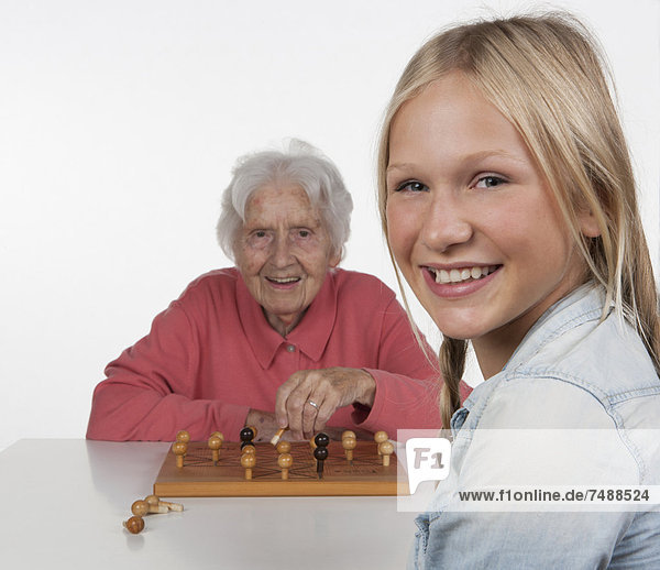 Senior woman and teenage girl playing Fox And Hen Game  smiling