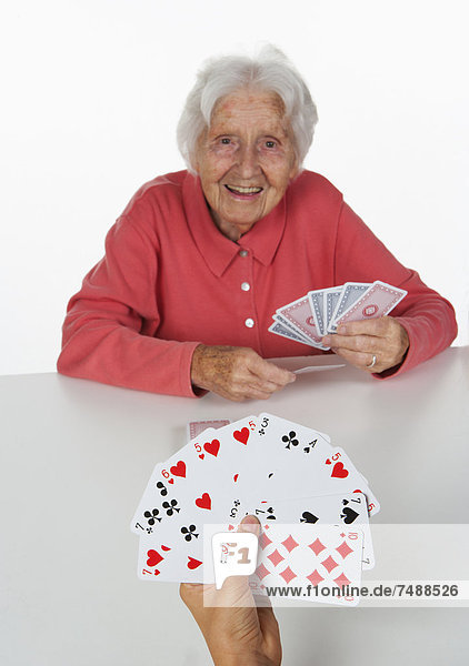 Senior woman and teenage girl playing cards  smiling