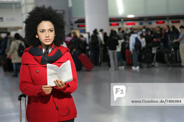 Young African American woman reading pamphlet in airport.