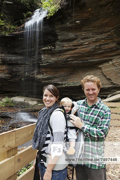 Caucasian family smiling by waterfall
