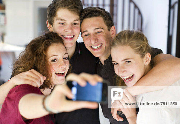 Happy young friends taking self portrait through cell phone