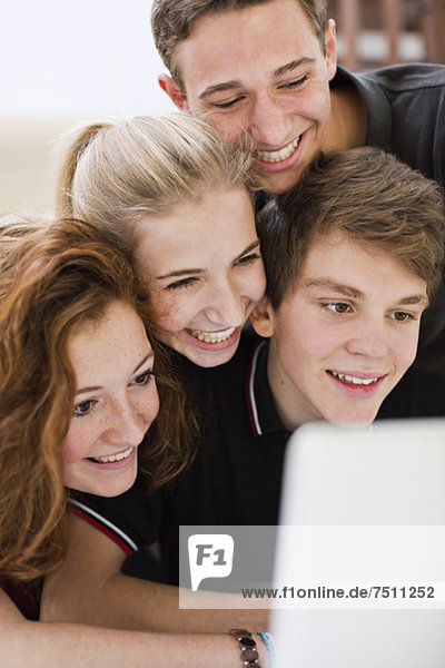 Glückliche Teenager-Freunde beim Betrachten des Laptop-Bildschirms