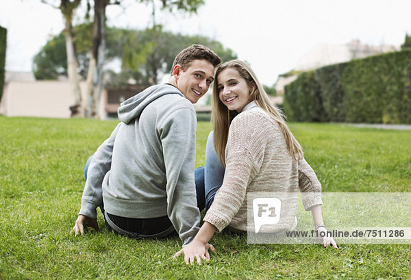 Portrait eines glücklichen jungen Paares  das zusammen im Park sitzt.