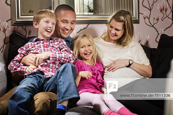 Porträt eines glücklichen Mädchens  das mit seiner Familie auf dem Sofa sitzt.