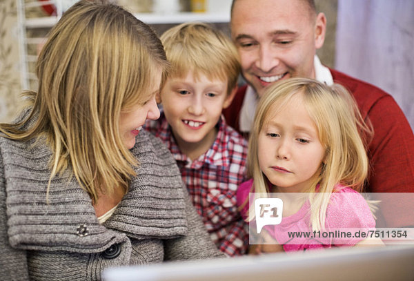 Glückliche vierköpfige Familie mit Laptop zu Hause