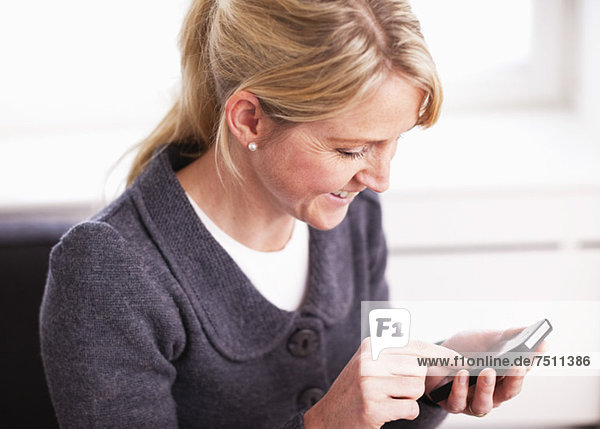 Glückliche Geschäftsfrau im mittleren Erwachsenenalter mit Smartphone