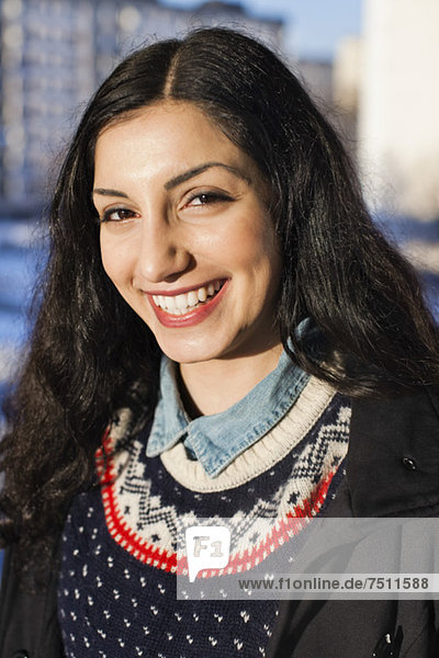 Porträt einer fröhlichen jungen Frau aus dem Nahen Osten  die im Freien lächelt.