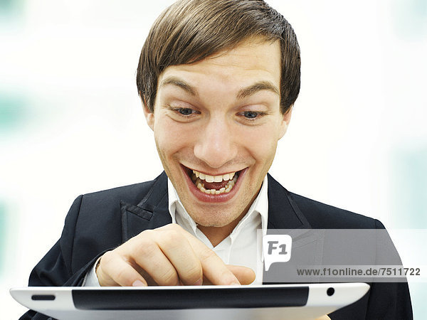 Geschäftsmann  Portrait  scrollt auf iPad  konzentriert  lachend