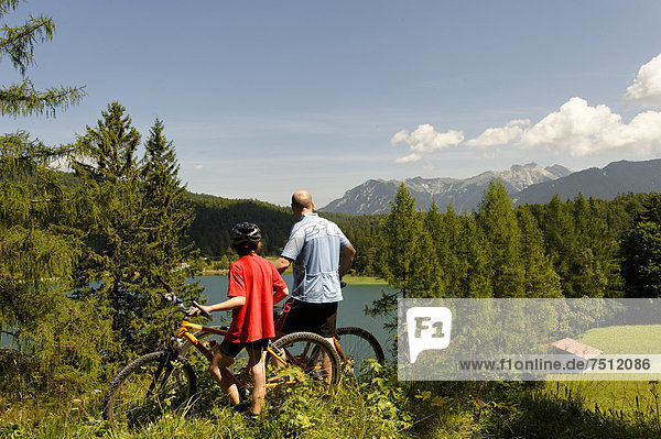 Cycling tour with mountain bikes  father and son in front of Lake Lautersee  Mittenwald  Karwendel Mountains  Werdenfelser Land  Upper Bavaria  Bavaria  Germany  Europe