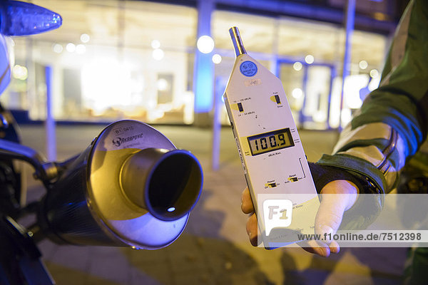 Police control  policeman holding a noise level meter beside the exhaust of a motorcycle whose noise reduction device has been removed  Theodor-Heuss-Strasse  Stuttgart  Baden-Wuerttemberg  Germany  Europe