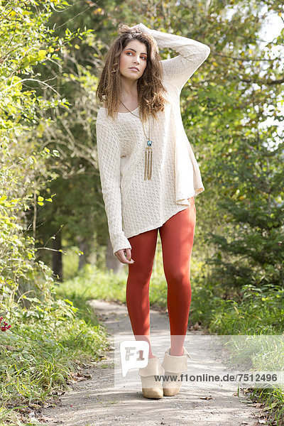 Junge Frau mit langem weißem Pullover und roter Strumpfhose  Outdoor