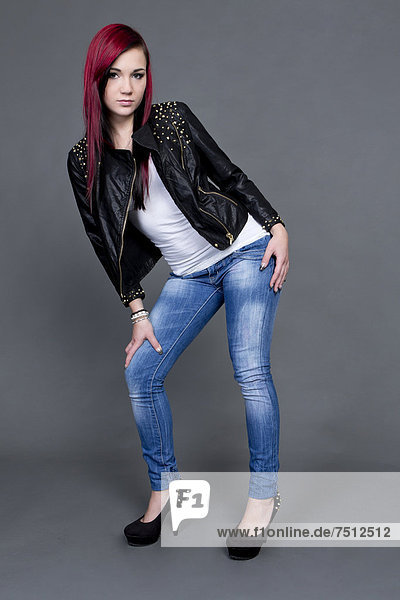 Junge Frau posiert in Lederjacke  Jeanshose und hohen Schuhen