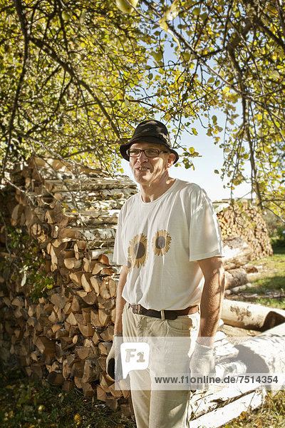 Mann im Obstgarten vor einem Holzstapel