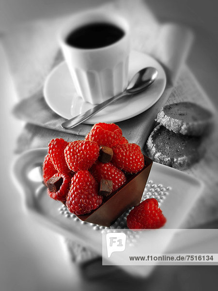 Stück Schokoladentorte mit Himbeeren und einer Tasse Kaffee