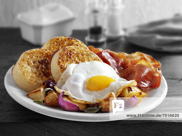 Frühstück mit Crumpets  Spiegelei  Frühstücksspeck  und Bratkartoffeln