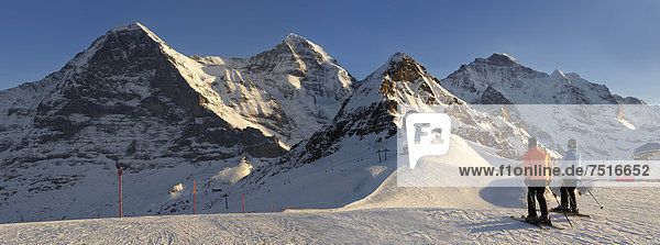 Skiers in winter  at Mannlichen  with Eiger and Jungfrau mountains behind  Swiss Alps  Switzerland  Europe