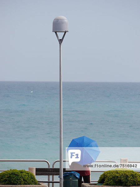 Person with umbrella overlooking the Mediterranean Sea  on the promenade in Finalpia  Riviera  Liguria  Italy  Europe