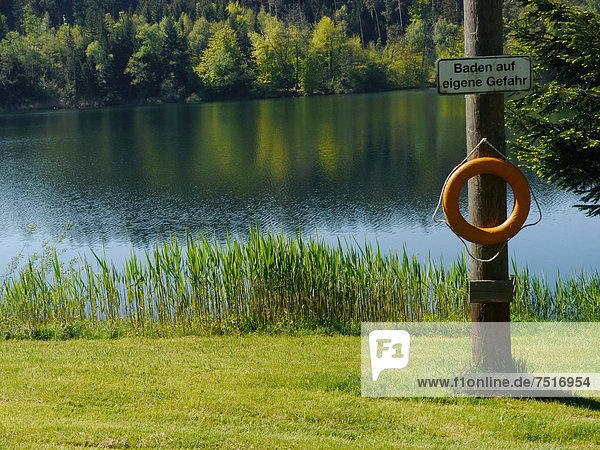 'Lifebuoy and sign ''Baden auf eigene Gefahr''  German for ''swimming at your own risk''  Degersee lake  Baden-Wuerttemberg  Germany  Europe'