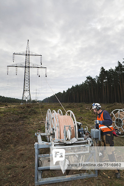 Vorseilzugarbeiten an der 380-kV-Fernleitung des Übertragungsnetzbetreibers 50Hertz  Leitungsseile werden von Mast zu Mast gezogen  mit denen später die eigentlichen elektrischen Leiterseile montiert werden  Freileitungsmonteure in den Strommasten nehmen die Seile auf  Gudow  Schleswig-Holstein  Deutschland  Europa