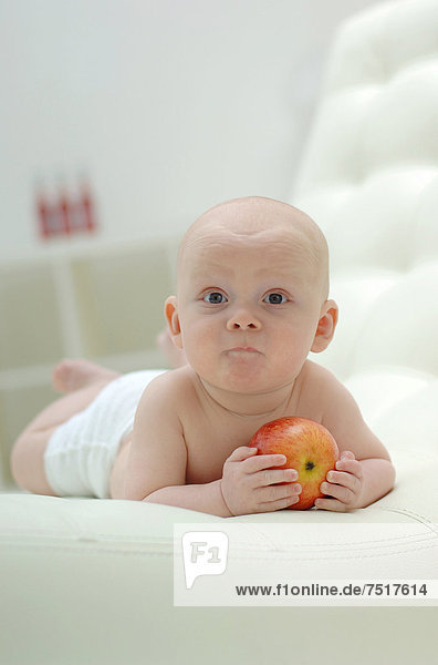 Baby liegt auf dem Bauch mit Apfel