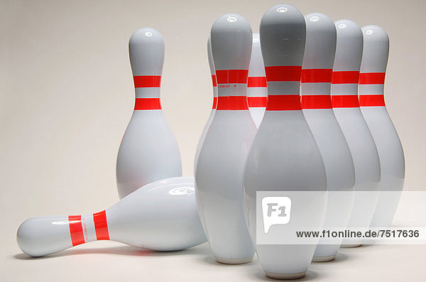 Gruppe von aufgestellten Bowlingkegeln mit einem umgefallenen Kegel