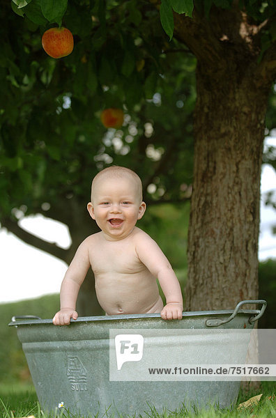 Baby  einjährig  badet in Zinkwanne im Freien