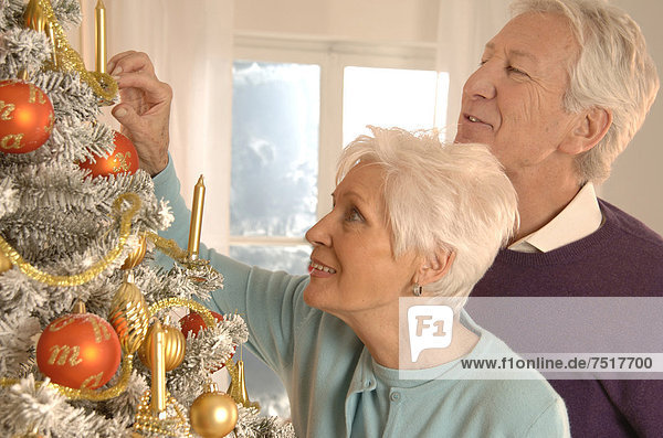 Älteres Paar schmückt Weihnachtsbaum