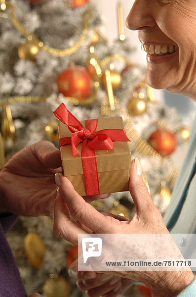 Ältere Frau wird am Weihnachtsbaum beschenkt