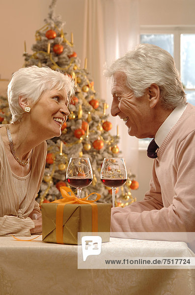 Geschenk sitzend Rotwein frontal Weihnachtsbaum Tannenbaum reifer Erwachsene reife Erwachsene