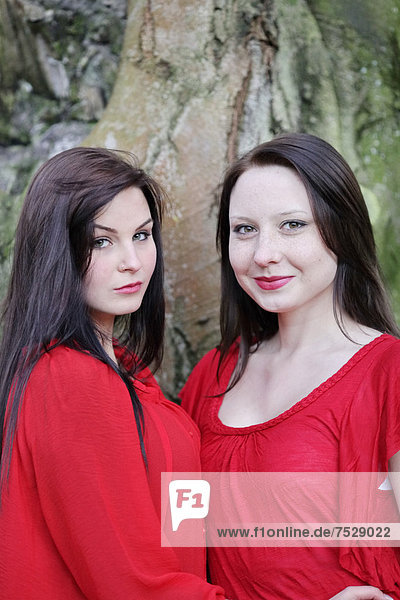 Two sisters in front of an old tree  portrait