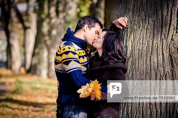 Junges Paar beim Küssen in einem Park im Herbst