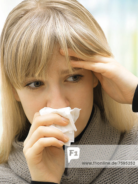 Junge Frau mit Taschentuch  putzt sich die Nase  krank  Allergie  traurig