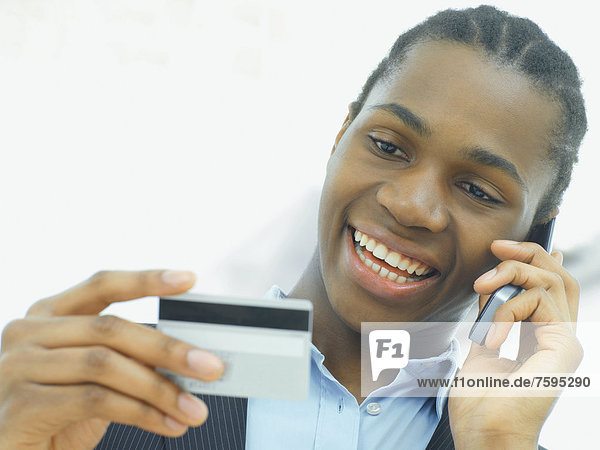 Geschäftsmann  afroamerikanisch  telefoniert  mit Kreditkarte