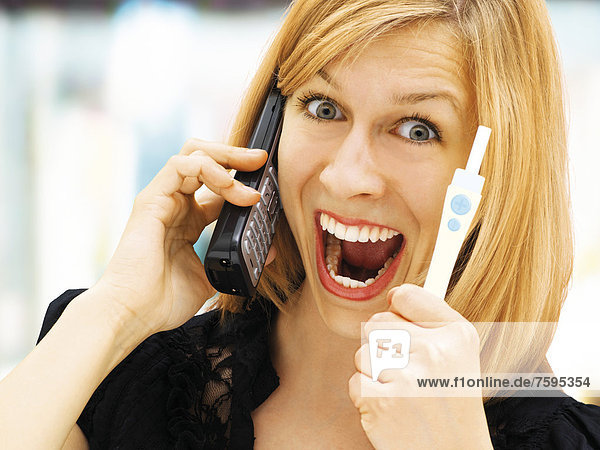 Woman holding a pregnancy test  using a telephone  happy